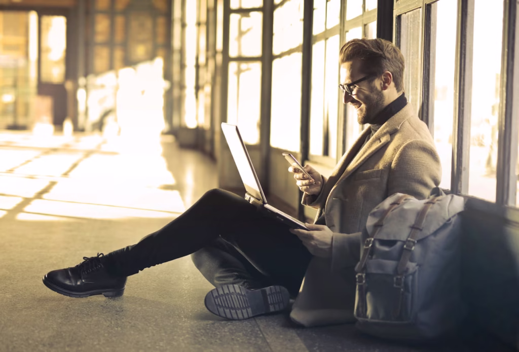 Man sitting with a laptop and smartphone, representing digital nomad lifestyle and remote work.